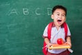 Child boy from kindergarten in student uniform with school bag holding red apple on books Royalty Free Stock Photo