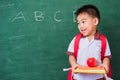 Child boy from kindergarten in student uniform with school bag holding red apple on books Royalty Free Stock Photo