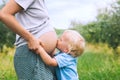 Child boy kissing belly of pregnant her mother on nature backgro Royalty Free Stock Photo