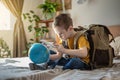 A child boy with backpack is playing with a toy airplane and a globe of the earth. Going on a journey towards adventure Royalty Free Stock Photo
