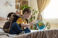 A child boy with backpack is playing with a toy airplane and a globe of the earth. Going on a journey towards adventure Royalty Free Stock Photo