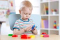 Child boy learning to use colorful play clay in nursery room