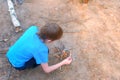 Child boy making bonfire from firewoods branches nature sitting near it.