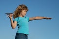Child boy with paper plane against blue sky. Child dreaming, throwing paper plane, toy airplane. Imagination, kids Royalty Free Stock Photo