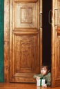 Child boy peeks out of the door with a christmas gift box Royalty Free Stock Photo