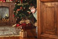 Child boy peeks out of the door with a christmas gift box Royalty Free Stock Photo