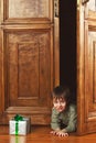 Child boy peeks out of the door with a christmas gift box Royalty Free Stock Photo