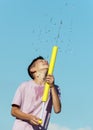 Child boy play with water gun, pours water on hot summer day. Fun kids game outdoor, refreshing in sunny, warm weather