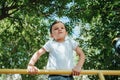 child boy playing and climbing on horizontal bars on playground in summer