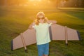 Child boy playing and dreaming about summer vacation and travel at sunset. Kids imagination and freedom concept. Royalty Free Stock Photo