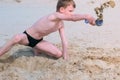 Child boy playing on sea sand beach digging shovel deep hole and throwing sand. Royalty Free Stock Photo