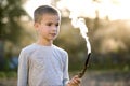 Child boy playing with smoking wooden stick outdoors
