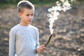 Child boy playing with smoking wooden stick outdoors