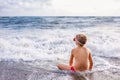 Child boy playing in the waves on the beach in summer sunset, kid watching sea waves and having fun Royalty Free Stock Photo