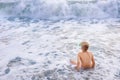 Child boy playing in the waves on the beach in summer sunset, kid watching sea waves and having fun Royalty Free Stock Photo