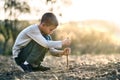 Child boy playing with wooden stick digging in black dirt ground outdoors Royalty Free Stock Photo