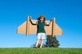 Child boy plays in an astronaut dreams of space. Happy child play with toy plane cardboard wings against blue sky. Kid Royalty Free Stock Photo