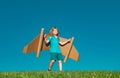 Child boy plays in an astronaut dreams of space. Happy child play with toy plane cardboard wings against blue sky. Kid Royalty Free Stock Photo