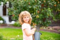 Child boy pouring water on the trees. Kid helps to care for the plants with a watering can in the yard garden. Royalty Free Stock Photo