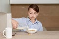 Child boy pours cornflakes into a white plate. The child prepares a breakfast. Royalty Free Stock Photo