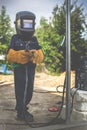 A child, a boy pretends to weld a fence. Welder`s costume, gloves, mask.