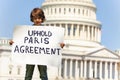 Protester holding sign uphold Paris agreement in hands