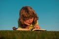 Child boy is reading a book on the spring park. Relaxing on the grass in the garden. Outdoor education. Kids imagination Royalty Free Stock Photo