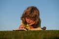 Child boy is reading a book on the spring park. Relaxing on the grass in the garden. Outdoor education. Kids imagination Royalty Free Stock Photo