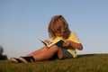 Child boy is reading a book on the spring park. Relaxing on the grass in the garden. Outdoor education. Kids success Royalty Free Stock Photo