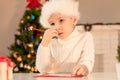 Child boy in red Santa hat writing a letter to Santa Claus. Christmas or New Year cozy holidays concept. Xmas time Royalty Free Stock Photo