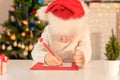 Child boy in red Santa hat writing a letter to Santa Claus. Christmas or New Year cozy holidays concept. Xmas time Royalty Free Stock Photo