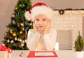 Child boy in red Santa hat writing a letter to Santa Claus. Christmas or New Year cozy holidays concept. Xmas time Royalty Free Stock Photo