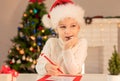 Child boy in red Santa hat writing a letter to Santa Claus. Christmas or New Year cozy holidays concept. Xmas time Royalty Free Stock Photo
