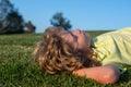 Child boy relax outdoors in sunny summer day. Happy child laying on green grass. Funny kid outdoor in spring garden