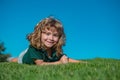 Child boy relax outdoors in sunny summer day. Happy child laying on green grass. Funny kid outdoor in spring garden