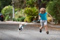 Child boy run with dog in leash walking outdoor. Kid playing with puppy. Children with pet friend. Royalty Free Stock Photo