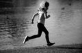 Child boy running outdoors. Kid running in a summer park. Kids running on green meadow against sea or lake. Royalty Free Stock Photo