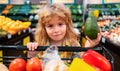 Child boy is shopping in a supermarket. Healthy food for young family with kids. Portrait of smiling little child with Royalty Free Stock Photo