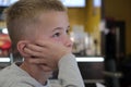 Child boy sitting in fast food restaurant behind empty table waiting for food Royalty Free Stock Photo