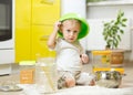 Child boy sitting on the kitchen floor and playing with flour. Royalty Free Stock Photo