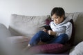 Child boy sitting on sofa watching cartoons on mobile  phone, School kid using cellphones learning lesson on internet, Home Royalty Free Stock Photo