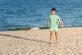 Child boy soccer player holding ball and ready for game or match on sandy beach. Beach football, sport, summer holidays Royalty Free Stock Photo