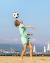 Child boy soccer player plays with soccer ball while having fun on sea beach. Kids games and leisure, summer holidays Royalty Free Stock Photo
