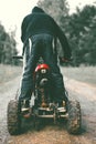 A child boy stands on an ATV wearing a black hoodie with his back to the camera. Quad bike. In the forest on a dirt road Royalty Free Stock Photo