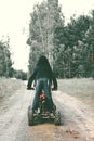 A child boy stands on an ATV wearing a black hoodie with his back to the camera. Quad bike. In the forest on a dirt road Royalty Free Stock Photo