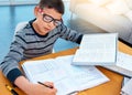 Child boy, student and writing on math book in studying, learning or education on table at home. Smart little kid busy Royalty Free Stock Photo