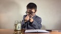 Child boy in a suit looking at the coins through magnifying glass. Posible investment research wealth growth concept