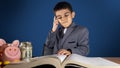 Child, boy in the suit thinking over the book. Investing in education concept Royalty Free Stock Photo