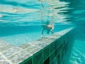 A child boy is swimming underwater in a pool, smiling and holding breath, with swimming glasses Royalty Free Stock Photo