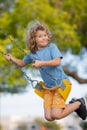 Child boy on swing. Kid swinging on playground. Cute excited amazed child on swing. Cute child swinging on a swing Royalty Free Stock Photo